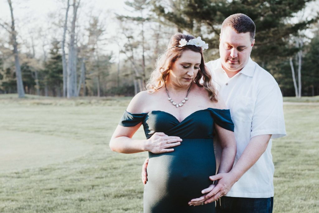 A photo of a pregnant woman and her husband looking at her belly