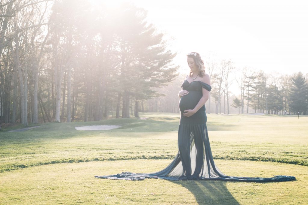 A photo taken at sunset of a pregnant woman in a gown