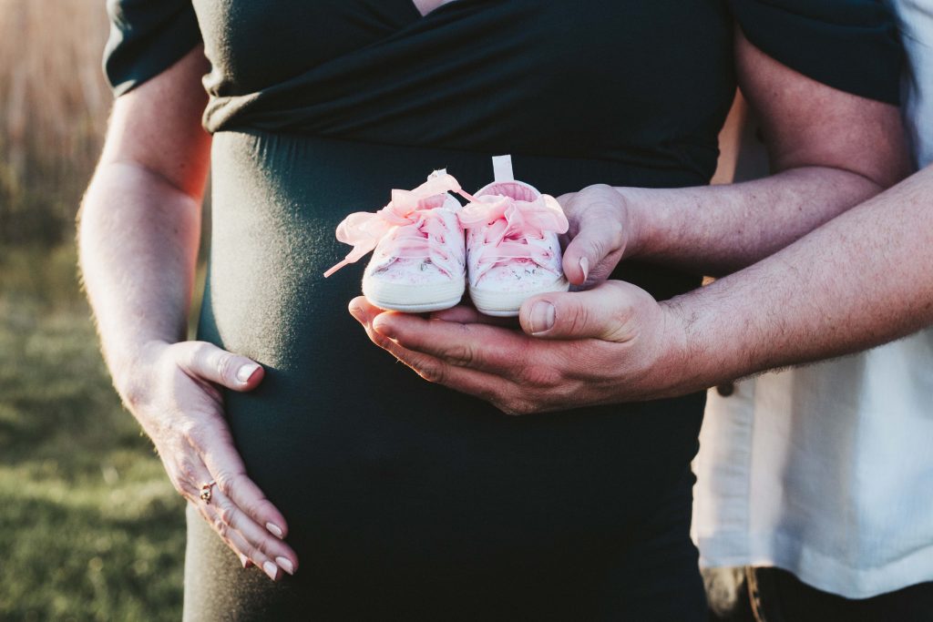 A close up photo of mom and dad holding baby shoes 